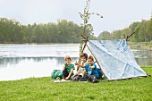 Selbst gebautes Zelt am Fluss mit Kindern