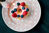 Doughnut decorated with fresh berries and birthday-cake candle