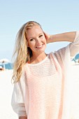 A blonde woman on the beach wearing a see-through woollen jumper