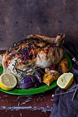 Roast chicken on a bed of vegetables with lemons