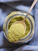 Moringa powder (superfood) on a spoon and in a jar
