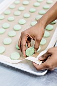 Green macaroons being removed from a baking tray