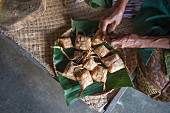 Asiate erstellt kleine Päckchen aus getrockneten Blättern