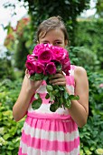 Girl wearing pink and white striped batik dress and holding pink roses