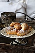 Mini croissants on a vintage cake plate on a wooden tray with decorations