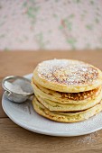A stack of pancakes with icing sugar