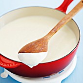 Béchamel sauce in a pan with a wooden spoon