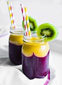 Two layer smoothies with straws in screw-top jars