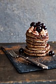 A stack of pancakes with cherries and cream