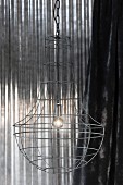 Wire lampshade in front of shiny metal background