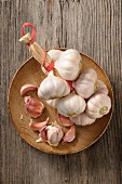 A string of garlic and cloves of garlic on a wooden plate