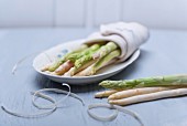 Green and white asparagus wrapped in a tea towel on a porcelain plate