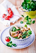 A salad with lambs lettuce, pasta, olives, tomatoes and pine nuts