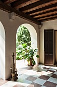 Antique candlesticks and house plant in loggia with chequered floor