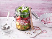 Layered quinoa and spinach salad with goat's cheese in a jar