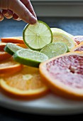 A woman taking a slice of lime from a tray of citrus fruit slices