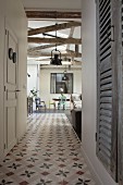 Ornamental floor tiles in hallway and view into open-plan interior with rustic half-timber beams