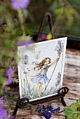 Romantische Postkarte mit Elfenmotiv auf Vintage Metallständer mit Lavendelblüten dekoriert