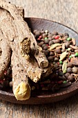 Mixed spices in a rustic wooden dish with liquorice root on top