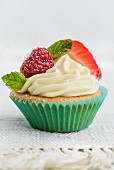 A cupcake decorated with berries and mint