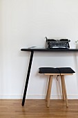 Typewriter on simple console table and wooden stool