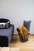 Cushions and blanket in wire basket next to sofa