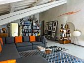 Living room with sloping ceiling, exposed beams, grey sofa and various shelves