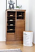 Paper sack next to vintage roll-front shoe cabinet in restored period apartment