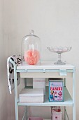 Glass cover and retro tins on pale blue serving trolley