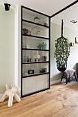 Metal door in front of shelving next to large macrame plant hanger