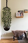 Large macrame plant next to stool covered in sheepskin blanket