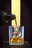 Whisky wird in Glas auf Eis gegossen