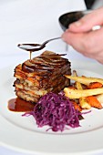 Layered lamb shoulder with potatoes served with red cabbage and root vegetables