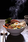 A steaming bowl of ramen noodle soup with mushrooms, prawns, pork belly and egg (Japan)