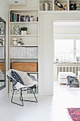 Classic metal mesh chair in front of open-fronted shelves in corner and mounted above door