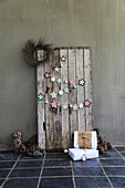 DIY garland made of crocheted doilies and Christmas baubles on a board wall with pinecones and gifts on the floor