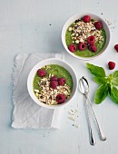 Bowls of smoothies with basil, cereals and raspberries