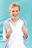 A young blonde woman wearing a white blouse with a jumper over her shoulder