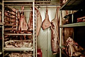 Pig carcasses hanging in cold room in a butcher's