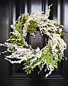 Door wreath of white flowers and decorative bird on black cassette door