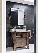 Blick durch offene Tür auf Waschtisch mit trogartigem Waschbecken und rustikaler Holz Unterschrank vor Mosaikfliesenwand