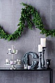 Christmas branch garland on wall above decorative arrangement with tea light glasses and candle holders