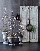 Three stylized decorative trees with light decoration in amphorae, vintage cupboard door with wicker