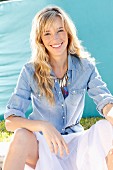 A young blonde woman wearing a denim shirt and a wide skirt