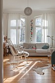 Wohnzimmer mit weißem Schaukelstuhl und Sofa am Fenster