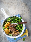 Lamb chops with potatoes, peas and asparagus in a pan