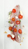 Raw fish fillet with tomatoes, garlic, butter and sage flowers