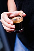 A hand holding a glass of coffee