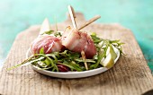 Grilled goat's cheeses wrapped in bacon on a rocket salad