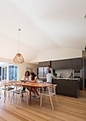 Family in open kitchen with dining table and parquet floor